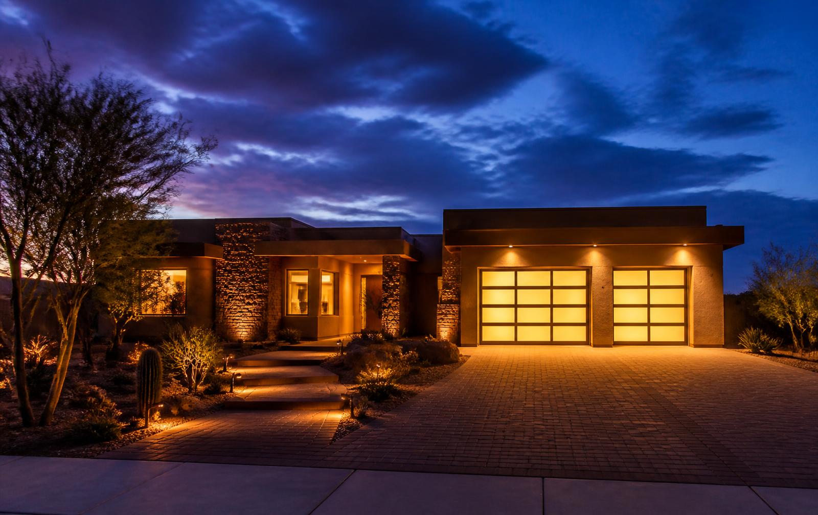 Home with a lit two-car garage at dusk